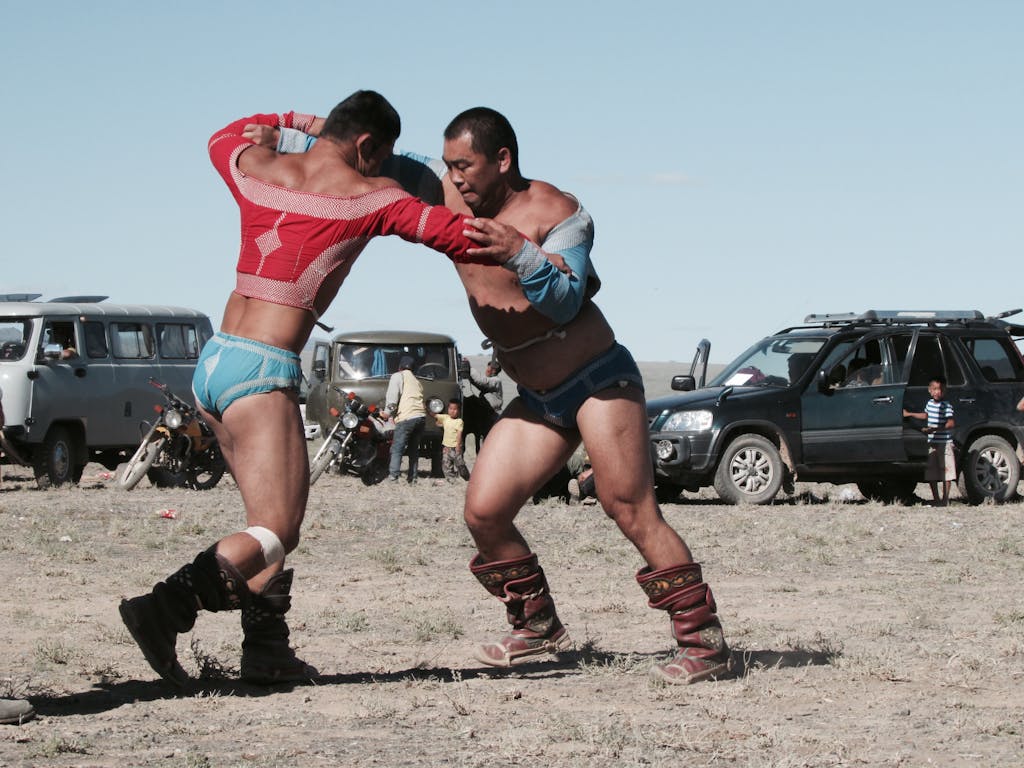 Mongolian Men in Traditional Costumes Wrestling in Field