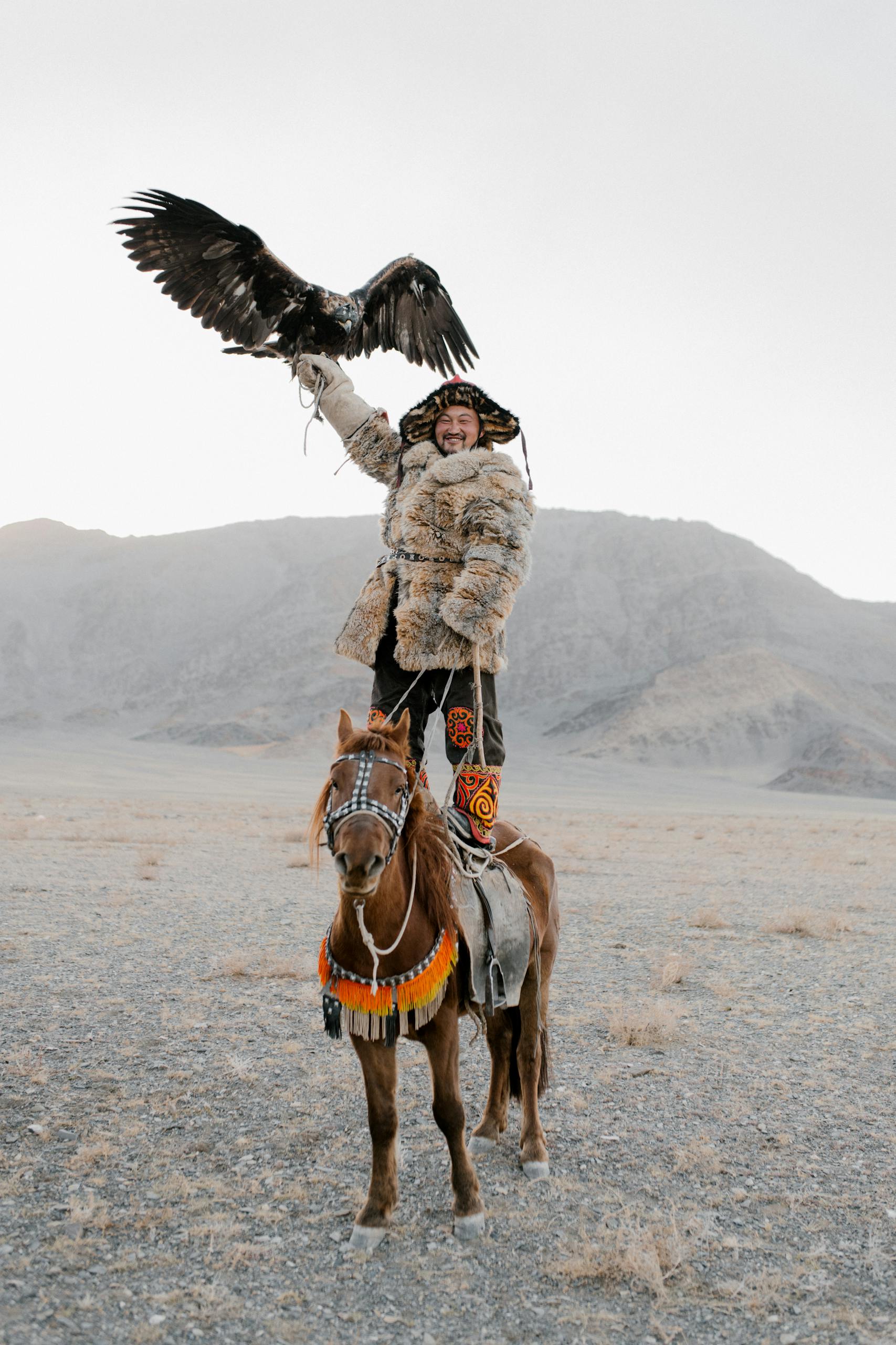 Hunter in Fur Coat Standing on Horse with Eagle on Hand