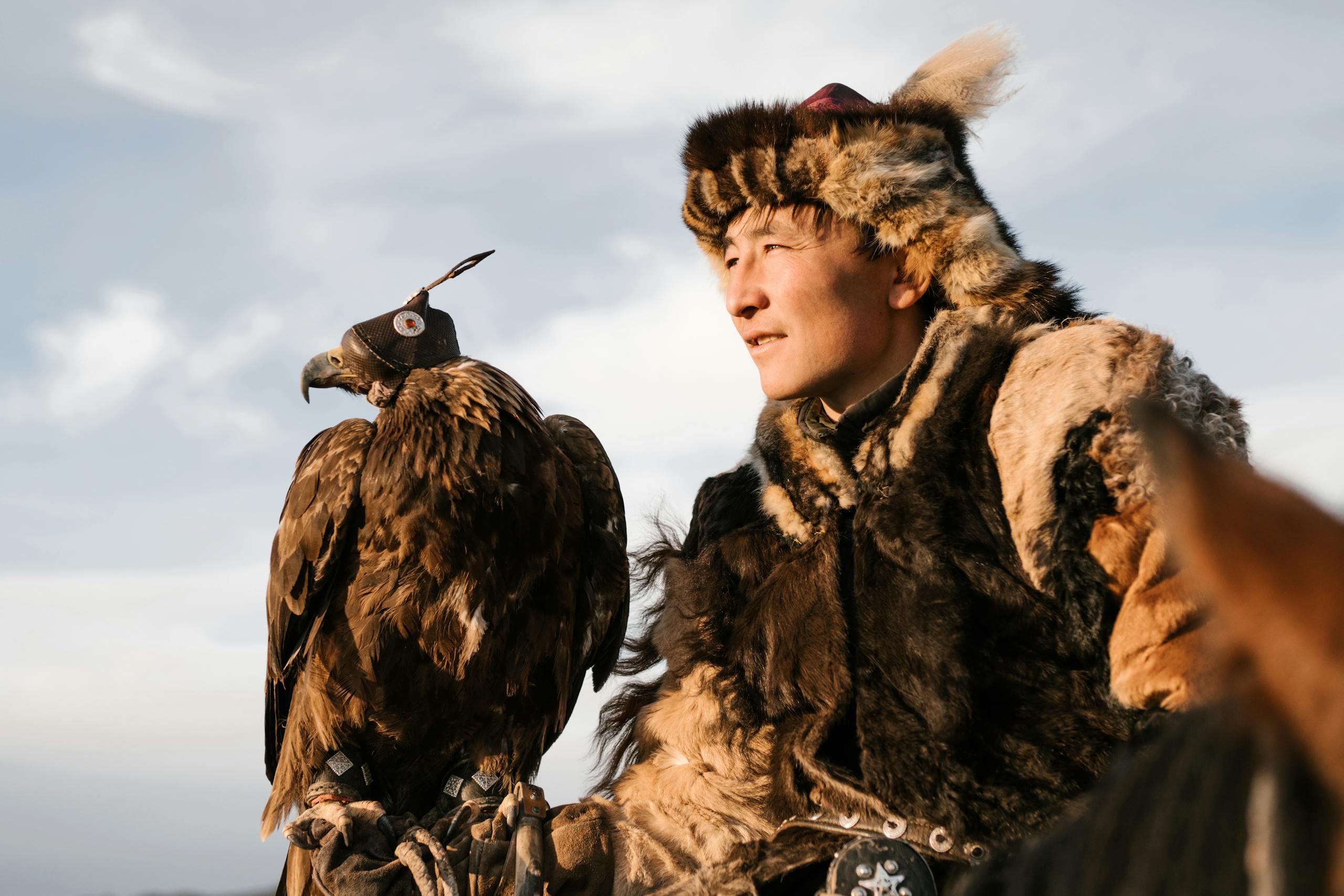 Man in Traditional Fur Clothes Holding Golden Eagle