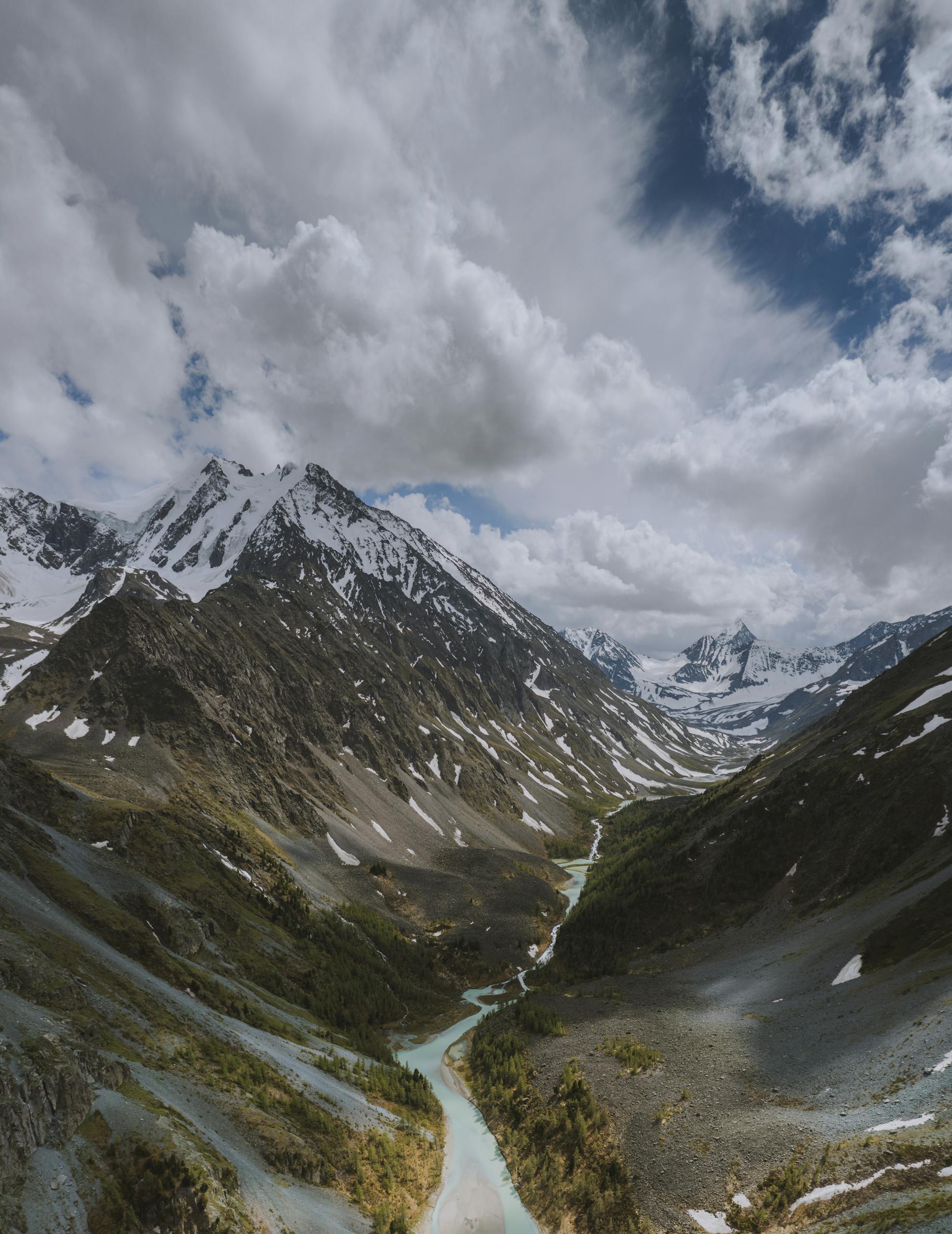 Breathtaking view of the snow-capped Altai Mountains and a serene river in Russia.