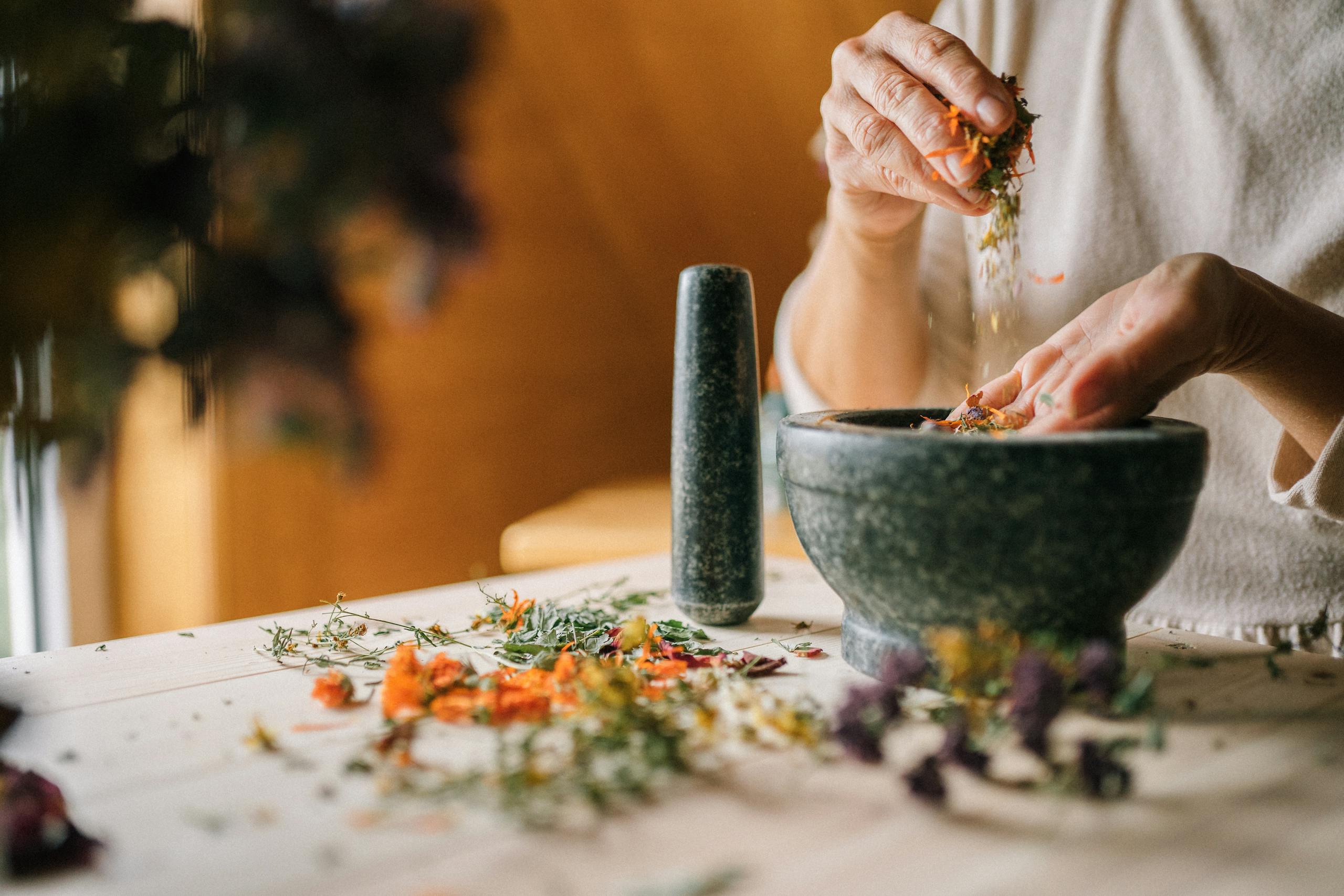 Mongolian Traditional Medicine 29 Close-up of hands grinding herbs and flowers in a mortar for natural remedies.